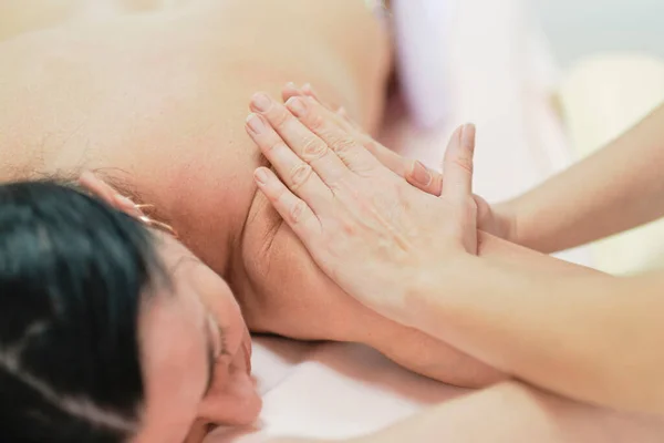 Fysiotherapeut die de rug en schouder van een vrouwelijke patiënt masseert. Over schouder uitzicht van masseur het uitvoeren van diepe weefsel massage van vrouwen terug naar pijn los te laten — Stockfoto