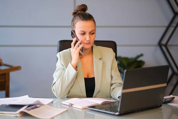 Busy female office worker. serious young female employee works in the office on her laptop. effective employee — Stock Photo, Image