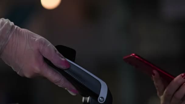 Menschliche Hand hält Smartphone über Zahlungsterminal. Kellner mit Gummihandschuhen. 4k Archivmaterial. Nahaufnahme-Video. Zeitlupenvideo. Zeitlupenaufnahme. — Stockvideo