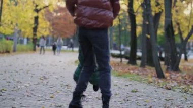 Güzel genç anne ve küçük oğlu parkta eğleniyor. Aile doğa yürüyüşünün tadını çıkarıyor. Mutlu annelik kavramı. 4K stok görüntüsü. Videoyu kapat. Yavaş çekim videosu. Yavaş çekim.