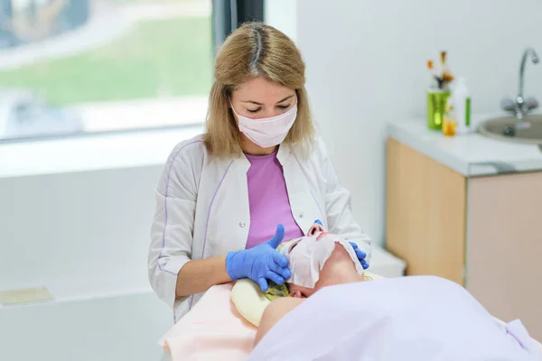 Vrouwelijke schoonheidsspecialiste op het werk in het kuuroord. Portret van een jonge vrouwelijke professionele cosmetoloog. Beroep in de gezondheidszorg, medische carrière. Jonge vrouw arts voorbereiding patiënt schoonheid procedures. — Stockfoto