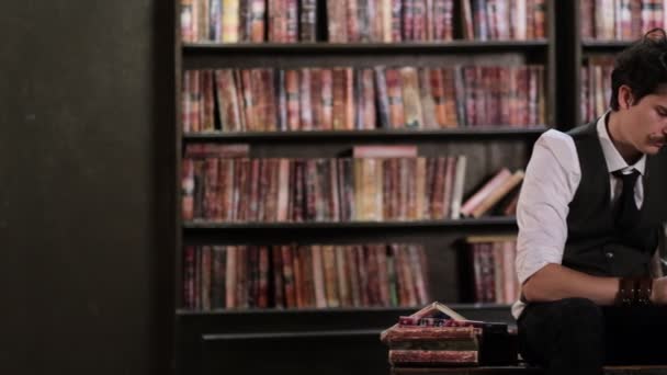 Homme élégamment habillé feuilletant des livres vintage dans une vieille bibliothèque sombre. vue rapprochée. Ralentissez la vidéo. images de stock — Video