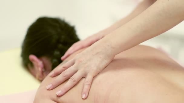 Fisioterapista che massaggia la schiena e la spalla di una paziente. Vista sulla spalla del massaggiatore che esegue un massaggio ai tessuti profondi. 4k filmati di magazzino. chiudere il video. Video al rallentatore. — Video Stock