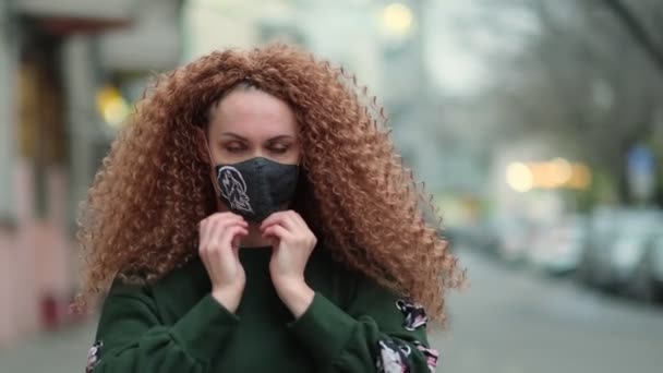 Pandemia do vírus Corona. Menina ruiva bonita com máscara médica. Retrato positivo lá fora. Fecha. Movimento lento — Vídeo de Stock