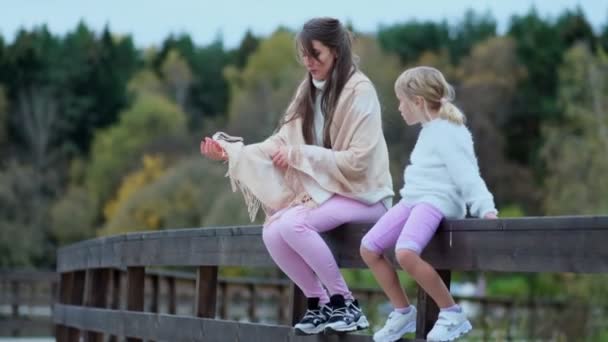 Mladá matka a dcera v parku na plotě a obdivovat krajinu, šťastná rodina tráví čas spolu. Zpomalené video. stock záběry — Stock video