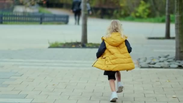 Retrato de una niña sonriente corriendo por el parque. Un niño feliz en el parque. Vídeo en cámara lenta. material de archivo — Vídeos de Stock
