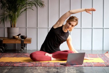 Çevrimiçi Eğitim. Evde egzersiz yapan, dizüstü bilgisayarda video dersi izleyen genç bir kadın. yumuşak odak
