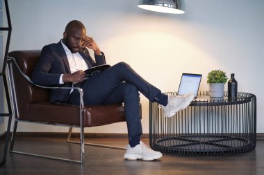 Sandalyede oturan takım elbiseli Afro-Amerikan bir adamın portresi. yumuşak odak