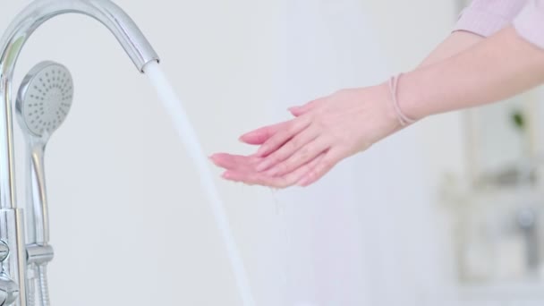 Kobiece ręce z bliska pod bieżącą wodą w łazience nad zlewem. strumień wody na kobiecej koncepcji pielęgnacji skóry dłoni. Filmik o zwolnionym tempie. materiał magazynowy — Wideo stockowe