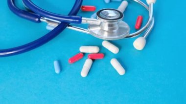 Tıbbi, tıbbi steteskop ve mavi arka planda haplar. Sağlık hizmeti ya da hastalık. Hastanede ya da eczanede ilaç ya da tablet. İlaç reçetesi. Yavaş çekim videosu. depolama görüntüleri