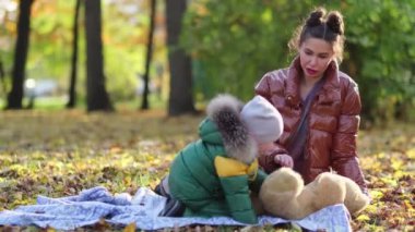 Genç anne ya da dadı parkta oynuyorlar. Annem sabun köpüğü üflüyor. Sonbaharda doğada yürümek. Mutlu bir aile. Manzarayı kapat. Yavaş çekim videosu. depolama görüntüleri