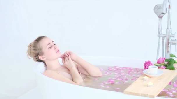 Красива сексуальна кавказька блондинка в бікіні лежить у квітковій ванні в курортному спа-салоні. Догляд за шкірою. Концепція молода жінка розслабляється у ванній. Повільне відео руху. фондовий знімок — стокове відео