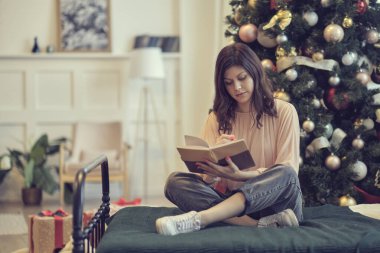 Güzel genç bayanın sarmaş dolaş kâğıt kitabının fotoğrafı. Noel tatili ve insanlar, yatak odasında kaleme ve deftere yazı yazan mutlu genç kadın kavramını benimsiyor.