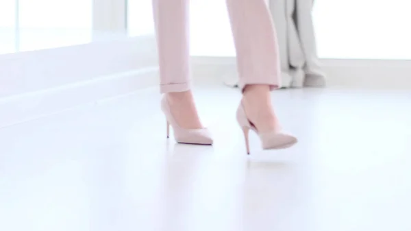 Yüksek topuklu ayakkabı giyen şık bir kadın. Yüksek topuklu ayakkabılı şık bir kadın. Yumuşak odaklı kadın beyaz ahşap zeminde yürüyor. — Stok fotoğraf