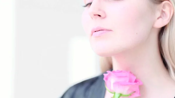 Красивая молодая женщина с нежным цветочком розы. Девушка чистая свежая кожа касаясь ее лица в цветах. мягкий фокус, избирательный фокус — стоковое фото
