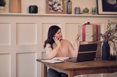 Masada oturan, dizüstü bilgisayarda yazan ve güncel kutu simgeleriyle telefonda konuşan güzel genç bir bayan. kutu evde iyi online alışveriş alır, posta sevkiyatı konsepti