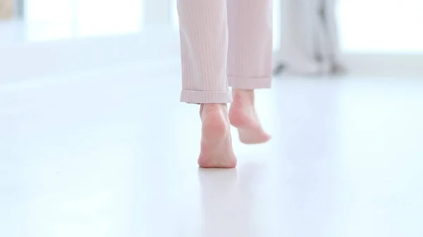 Side close up view of unrecognizable woman feet legs, barefoot girl standing indoors inside of modern home enjoy warm wooden heated floor. soft focus — Stock Photo, Image