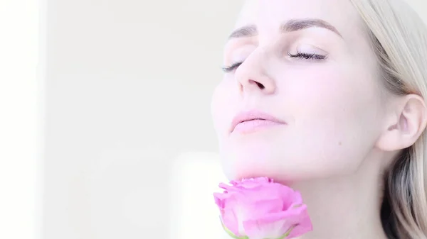 Belle jeune femme à la délicate fleur de rose. Fille nettoyer la peau fraîche touchant son visage dans les fleurs. foyer souple, foyer sélectif — Photo