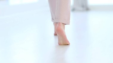 Tanınmayan kadın bacakları, çıplak ayaklı kız modern evin içinde sıcak ahşap zeminin keyfini çıkarıyor. yumuşak odak