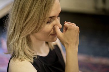 Burun deliğini değiştirerek nefes almak. Orta yaşlı kadın nefes egzersizleri yapıyor yoga, meditasyon, pranayama. Yakın plan, parmaklar burnu kapatır, Nadi Shodhana nefes alır.