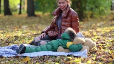 Genç anne ya da dadı parkta oynuyorlar. Annem sabun köpüğü üflüyor. Sonbaharda doğada yürümek. Mutlu bir aile. Manzarayı kapat. Yavaş çekim videosu. depolama görüntüleri