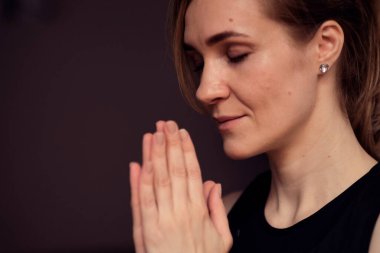 Orta yaşlı bir kadın gözleri kapalı meditasyon yapıyor. Elleri dua pozisyonunda yoga yapıyor..