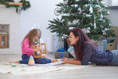 Pozitif, genç bir kadın anne, bir festival stüdyosunda yerde oturuyor ve küçük bir kızla oynuyor.