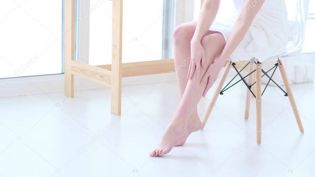 woman touch her smooth and soft skin on legs, enjoy beauty procedures. young asian woman applying cream and lotion touch foot dry on bed. Copy space.