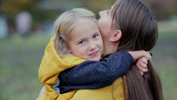 Дочка обіймає матір на природі. Красива молода жінка і її чарівна маленька донька обіймаються і посміхаються. Дочка обіймає матір на природі . — стокове відео