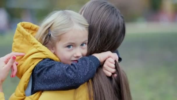Filha abraçando a mãe na natureza. Mulher bonita e sua filhinha encantadora estão abraçando e sorrindo. Filha abraçando mãe na natureza. — Vídeo de Stock