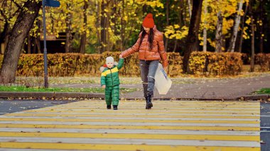 Anne ve küçük çocuk yaya geçidinden karşıya geçiyorlar. Trafik kuralları. Büyük şehirde yaya güvenliği.