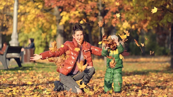 Anya és fia őszi leveleket dobálnak az őszi parkban, családi szórakozás. család élvezi a sétát a természetben. boldog anyaság koncepciója. — Stock Fotó