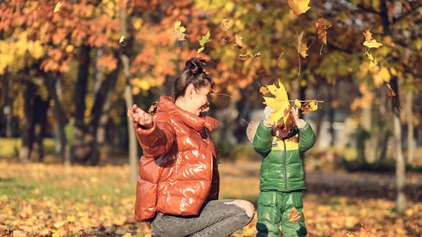 Mama i syn rzucają jesiennymi liśćmi w jesiennym parku, rodzinna zabawa. rodzina ciesząca się spacerem w przyrodzie. szczęśliwa koncepcja macierzyństwa. — Zdjęcie stockowe