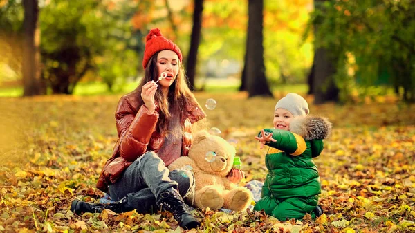 Adult mother or nanny blows bubbles for a little boy. happy motherhood. cute kid playing in the park. — Stock Photo, Image