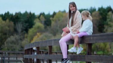 Parktaki çitin kenarındaki genç anne ve kız manzaraya hayran kalıyor, mutlu aile birlikte vakit geçiriyor. Yavaş çekim videosu. depolama görüntüleri
