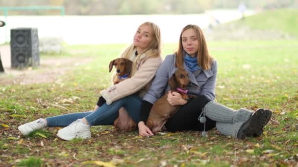 Zwolnij trochę. Dwie dziewczyny w parku bawią się z psami. związek sióstr. Spędź dzień w parku grając i bawiąc się. zbliżenie strzał wideo. — Wideo stockowe