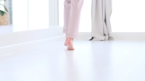 Side närbild av oigenkännlig kvinna fötter ben, barfota flicka står inomhus i moderna hem njuta av varm trä uppvärmda golv. mjukt fokus. Slow motion-video. Beståndsbilder — Stockvideo