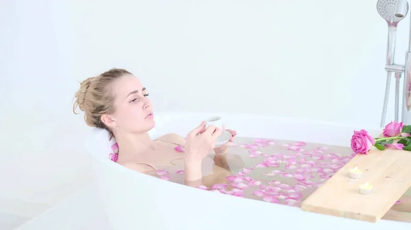 Linda menina loira caucasiana de biquíni deitado em banho de flores no Resort Day Spa Salon. Terapia de Cuidados com a pele. Conceito jovem mulher relaxante no tubo de banho. — Fotografia de Stock