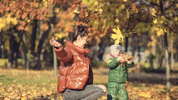 Mamma och son kastar höstlöv i höstparken, familjekul. familjen njuter av en promenad i naturen. Glad moderskap koncept. — Stockfoto