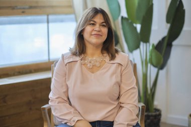 çekici orta yaşlı kadın evde dinleniyor. Gülümseyen kadın kameraya sırıtarak bakıyor. Başarılı orta yaşlı kadın gülümseyerek evde.