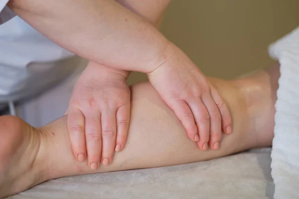 Detal rąk masujących mięśnie łydki ludzkiej.Terapeuta wywierający nacisk na kobiecą nogę. Ręce masażystki masującej nogi młodej kobiety w salonie spa. Pielęgnacja ciała w salonie spa dla młodej kobiety. — Zdjęcie stockowe