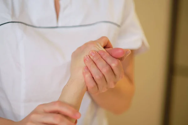 Massagem no pulso. o terapeuta de massagem põe a pressão em um ponto sensível em uma mão de mulheres. Fisioterapeuta massageando seus pacientes mão em consultório médico — Fotografia de Stock