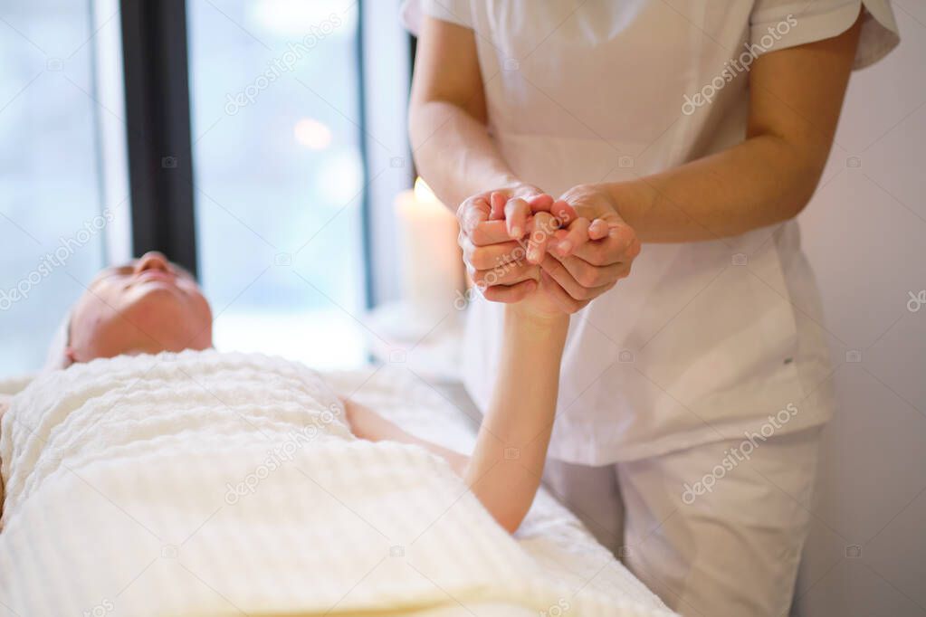 Wrist massage. massage therapist puts pressure on a sensitive point on a womans hand. Physiotherapist massaging her patients hand in medical office