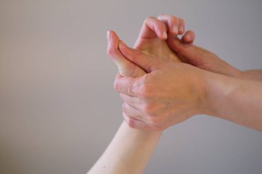 Bilek masajı. Masaj terapisti bir kadının eline hassas bir nokta basıyor. Fizyoterapist hastalarına masaj yapıyor.