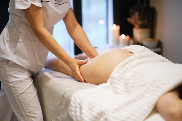 массажист делает антицеллюлитный массаж молодой женщине в спа-салоне. Концепция ухода за телом. Специальное антицеллюлитное лечение.