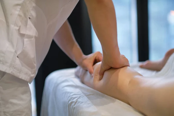 Detail van handen masseren menselijke kuitspier Therapeut uitoefenen druk op vrouwelijke been. Handen van massage therapeut masseren benen van jonge vrouw in spa salon. Lichaamsverzorging in spa salon voor jonge vrouw. — Stockfoto