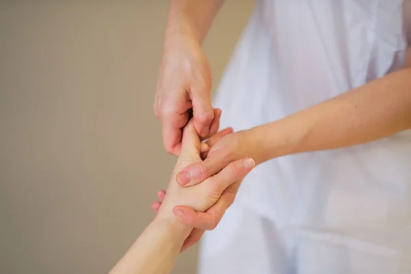 Massagem no pulso. o terapeuta de massagem põe a pressão em um ponto sensível em uma mão de mulheres. Fisioterapeuta massageando seus pacientes mão em consultório médico — Fotografia de Stock