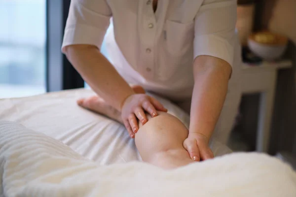 Dettaglio delle mani massaggiando il muscolo del polpaccio umano.Terapista che applica pressione sulla gamba femminile. Mani di massaggiatore massaggiando gambe di giovane donna in salone termale. Cura del corpo in salone spa per giovane donna. — Foto Stock