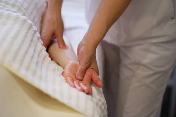 Masaż nadgarstka. masażystka wywiera nacisk na czuły punkt dłoni kobiety. Fizjoterapeutka masująca dłoń swoich pacjentów w gabinecie medycznym — Zdjęcie stockowe
