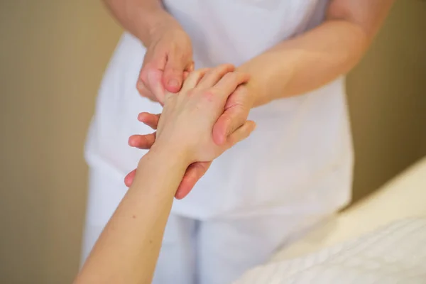 Masaje de muñeca. masajista ejerce presión sobre un punto sensible de la mano de una mujer. Fisioterapeuta masajeando a sus pacientes mano en consultorio médico — Foto de Stock